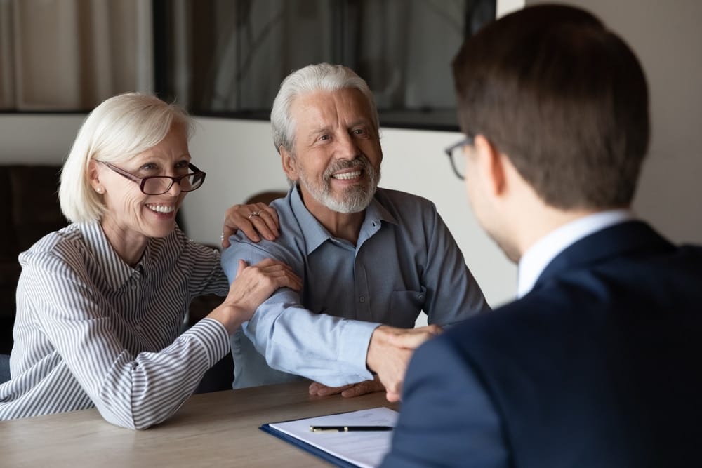 smiling,older,caucasian,man,and,woman,clients,shake,hand,greeting