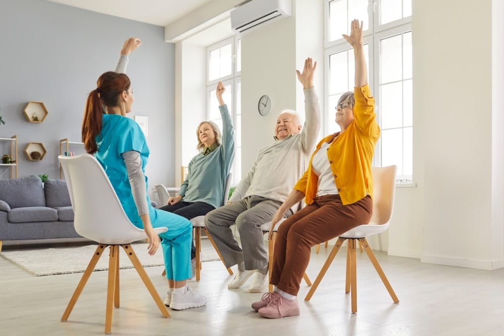 young,nurse,leading,seated,exercise,session,with,elderly,patients,in