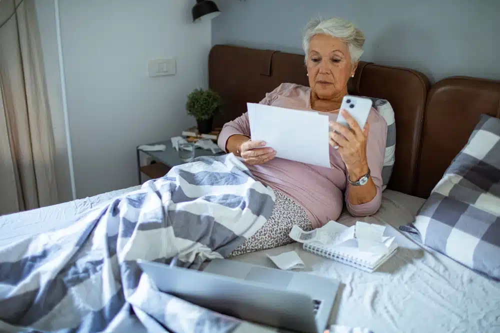 senior,woman,reading,bills,in,bed,at,home