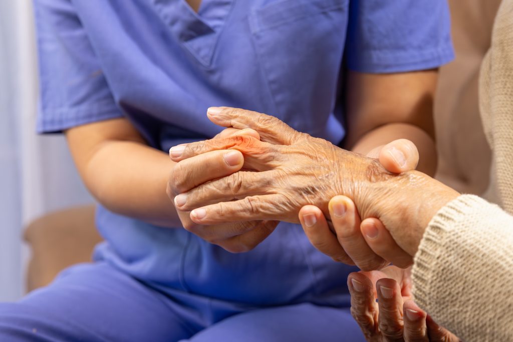 caregiver,massaging,finger,of,elderly,woman,in,painful,swollen,gout.