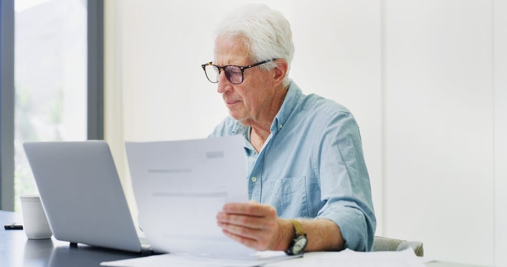 documents,,laptop,and,research,with,old,man,in,home,for