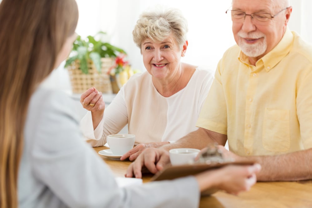 smiling,senior,woman,and,husband,talking,to,a,financial,advisor
