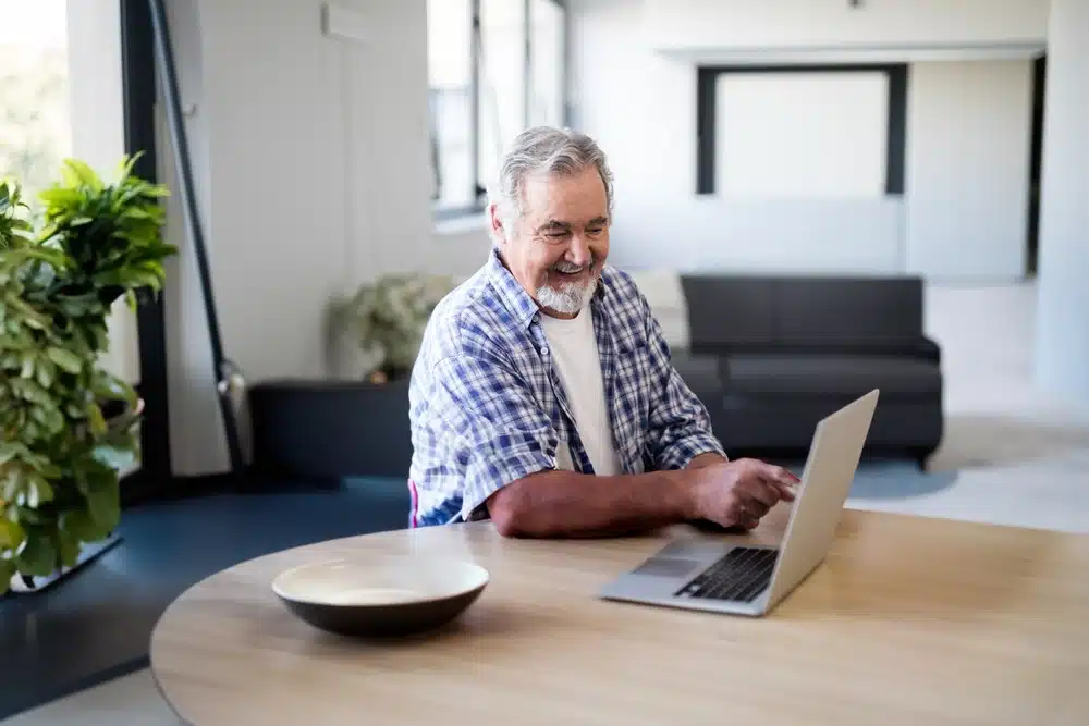 senior,man,using,laptop,at,home,,smiling,and,enjoying,leisure