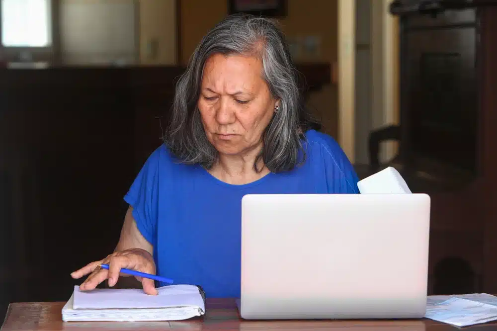 a,senior,latina,woman,sits,at,a,table,at,home,