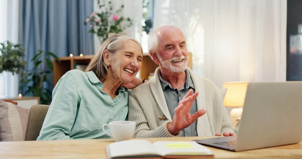 home,,happy,and,elderly,couple,with,wave,by,laptop,for