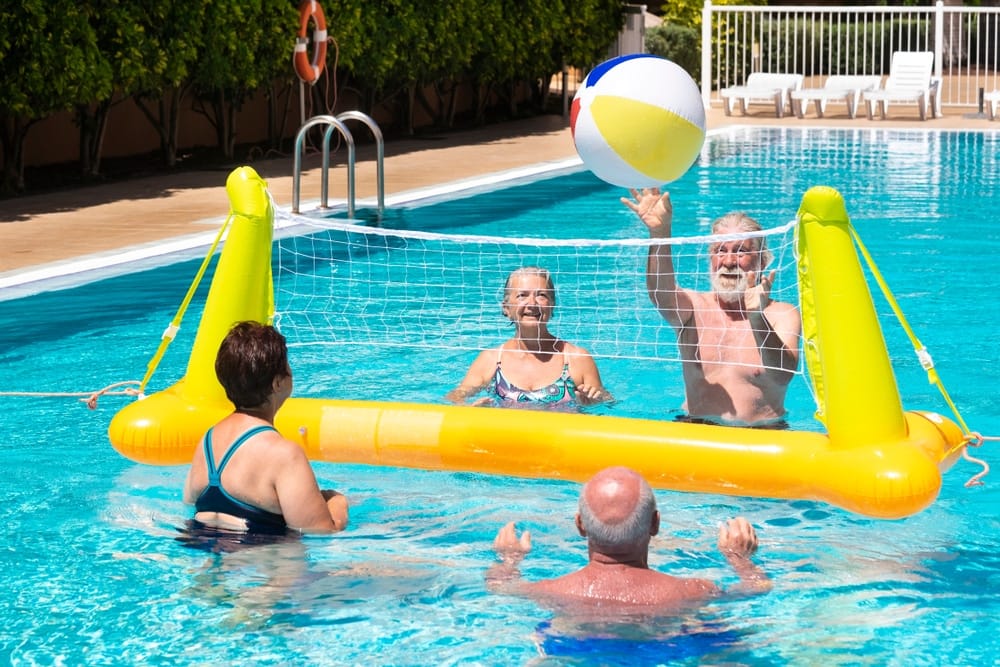 four,senior,people,playing,volleyball,in,the,pool,with,inflatable
