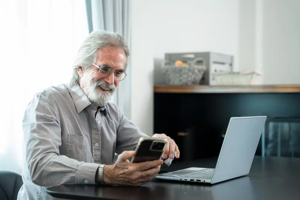 senior,man,using,mobile,phone,while,sitting,at,his,cozy