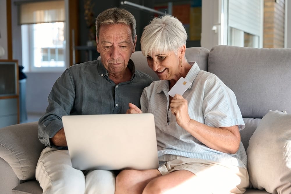happy,retired,couple,is,shopping,online,using,laptop,and,credit