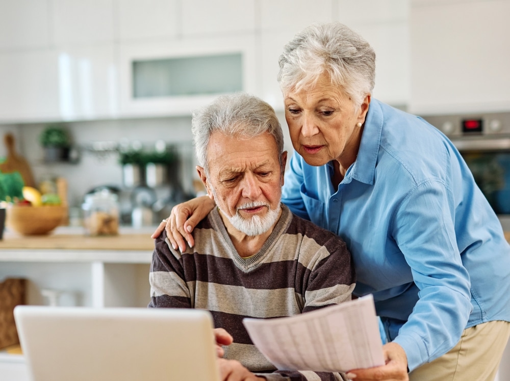 senior,couple,checking,bills,and,calculating,expenses,using,a,laptop