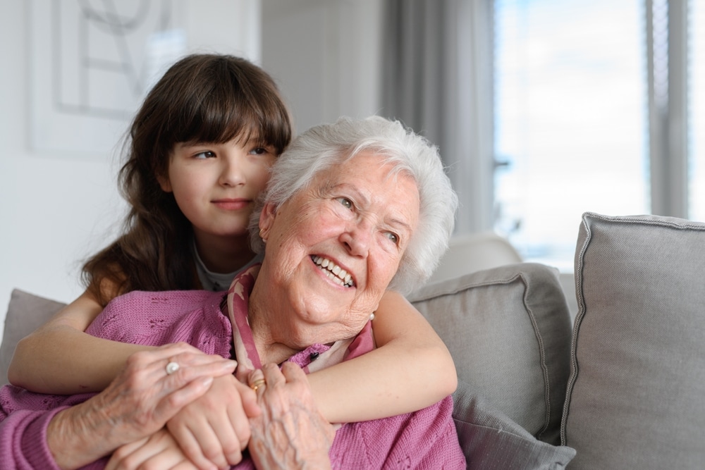 cute,girl,hugging,gradmother,from,behind.,portrait,of,an,elderly