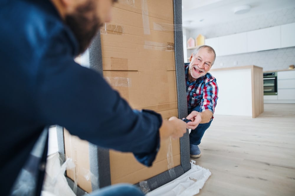 a,senior,man,helping,his,son,with,furnishing,new,house,