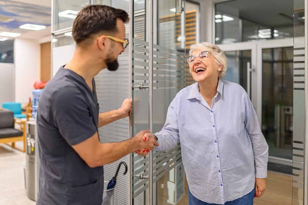 male,ophthalmology,doctor,greeting,happy,senior,woman,with,handshake,while