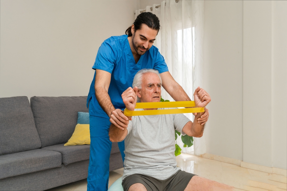 senior,man,exercising,with,resistance,band,with,the,help,of