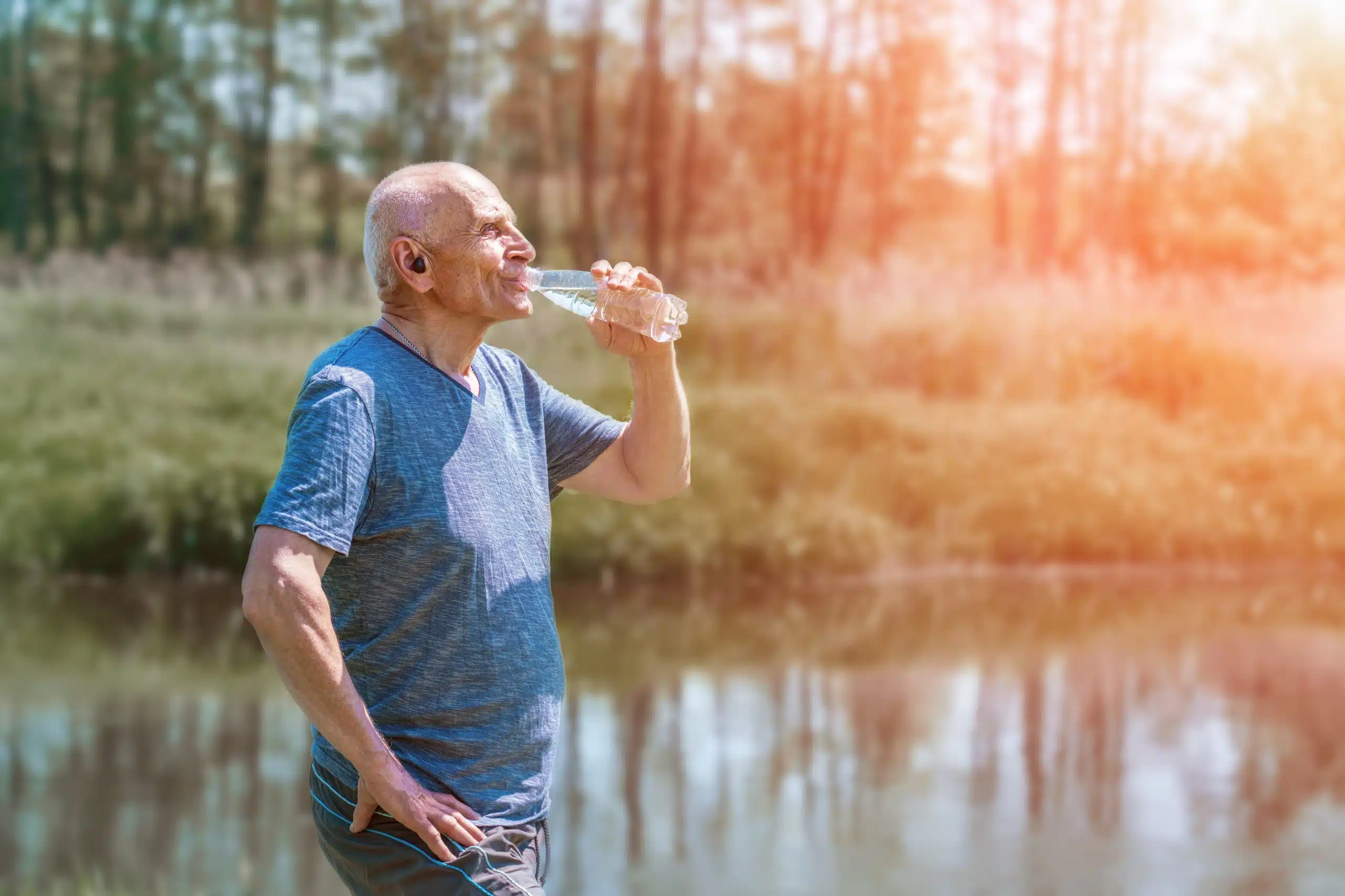 elder,man,in,headphones,in,ears,drinking,water,from,plastic