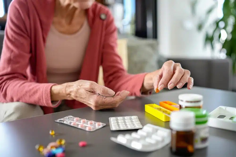 senior,woman,organizing,medications,at,home,,carefully,placing,pills,into