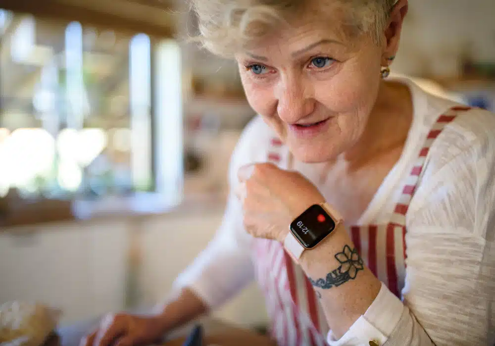 senior,woman,with,apron,and,smartwatch,indoors,at,home.