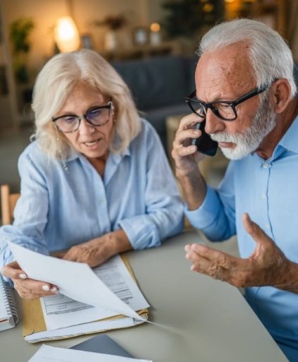 senior,couple,looking,at,documents,and,making,a,stressful,phone